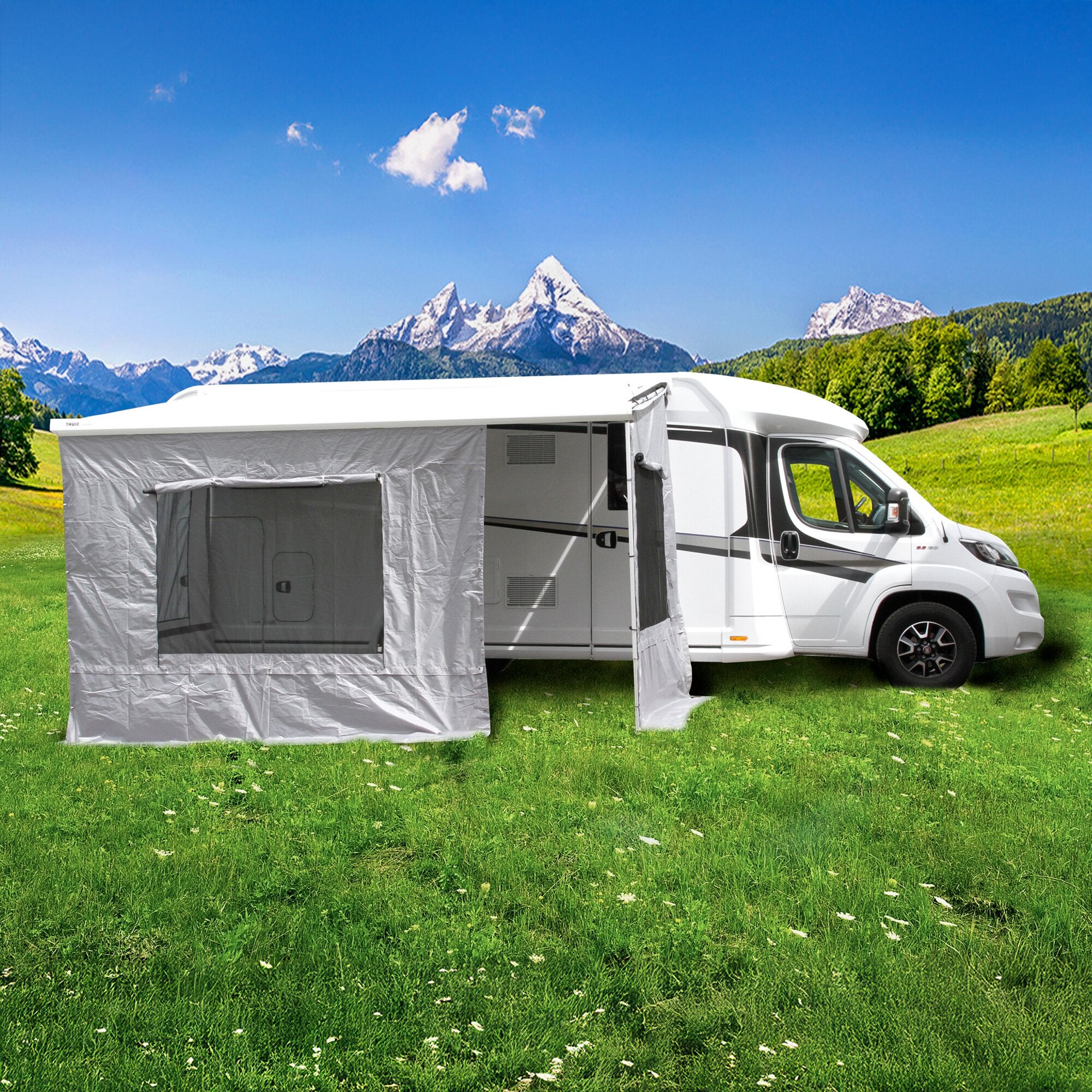 Thule Markisenzelt Camper Lounge am Seitenbereich eines weißen Wohnmobils; graues Zelt aus Stoff erweitert den Außenwohnraum vor Berglandschaft