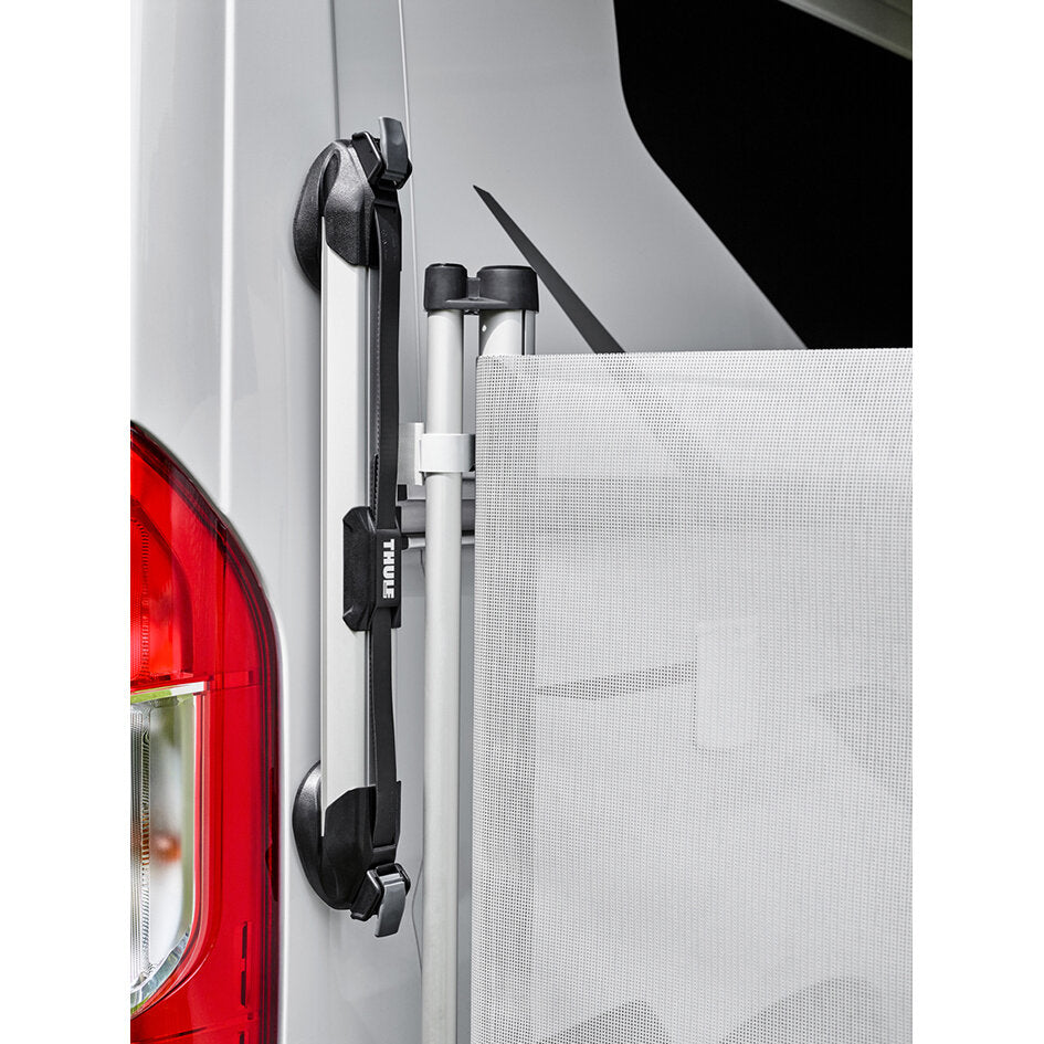 Seitliche Nahaufnahme eines Transporters mit montiertem Thule Windscreen: graues Mesh‑Panel, schwarzes Traggestell und passende Halterungen am Heck