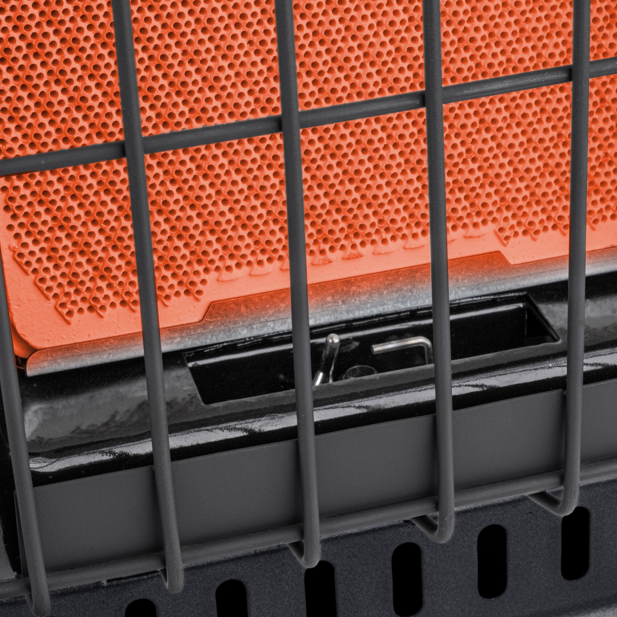 Detailaufnahme einer orangefarbenen Gehäusefront mit perforierter Oberfläche aus vielen kleinen runden Löchern, von schwarzen Gitterleisten durchzogen