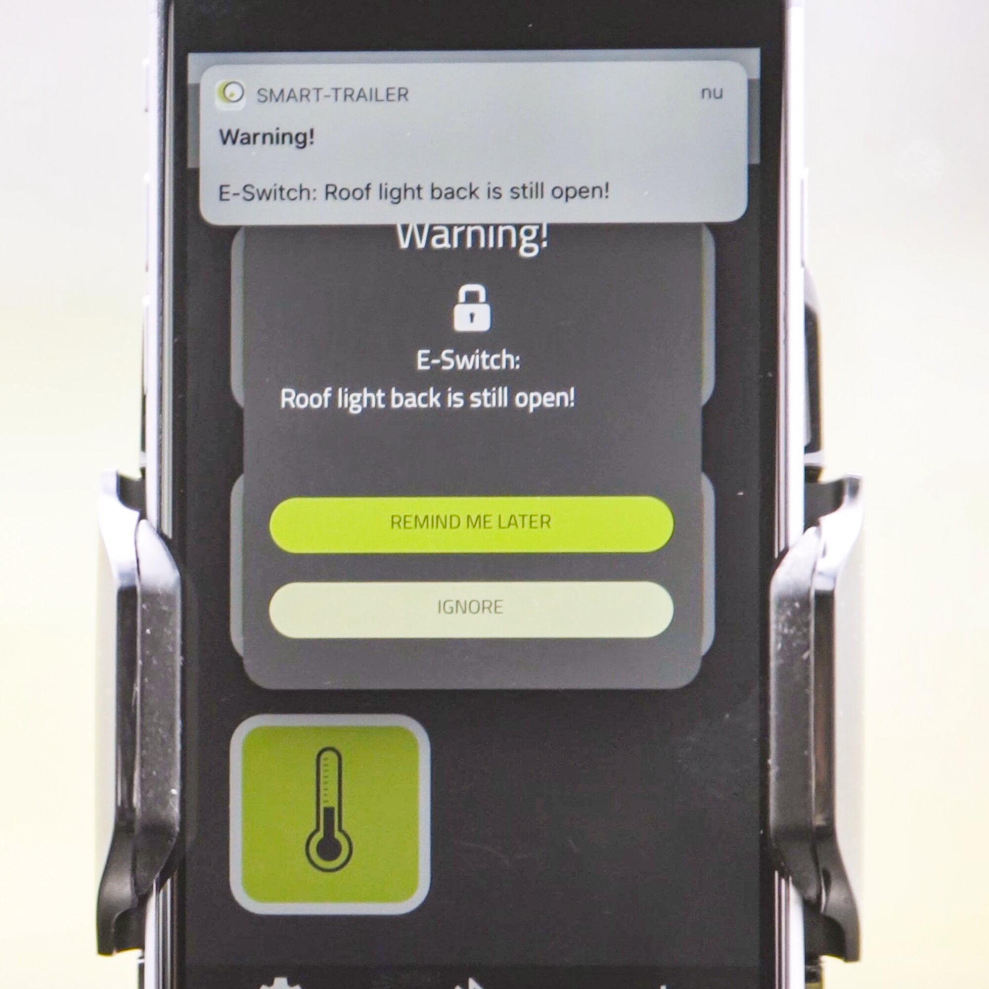 Smartphone zeigt Warnmeldung von SMART-TRAILER: E-Switch Roof light back is still open! grüne Taste Remind Me Later sichtbar