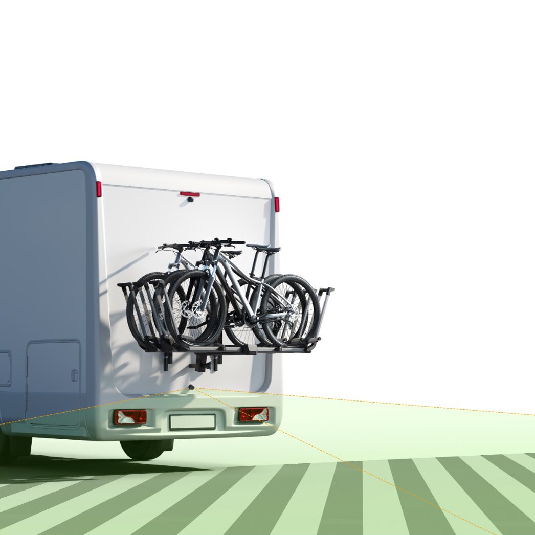 Rückseite eines weißen Wohnmobils mit Fahrradträger, auf dem mehrere Fahrräder montiert sind, gelbe Führungslinien auf dem Boden sichtbar