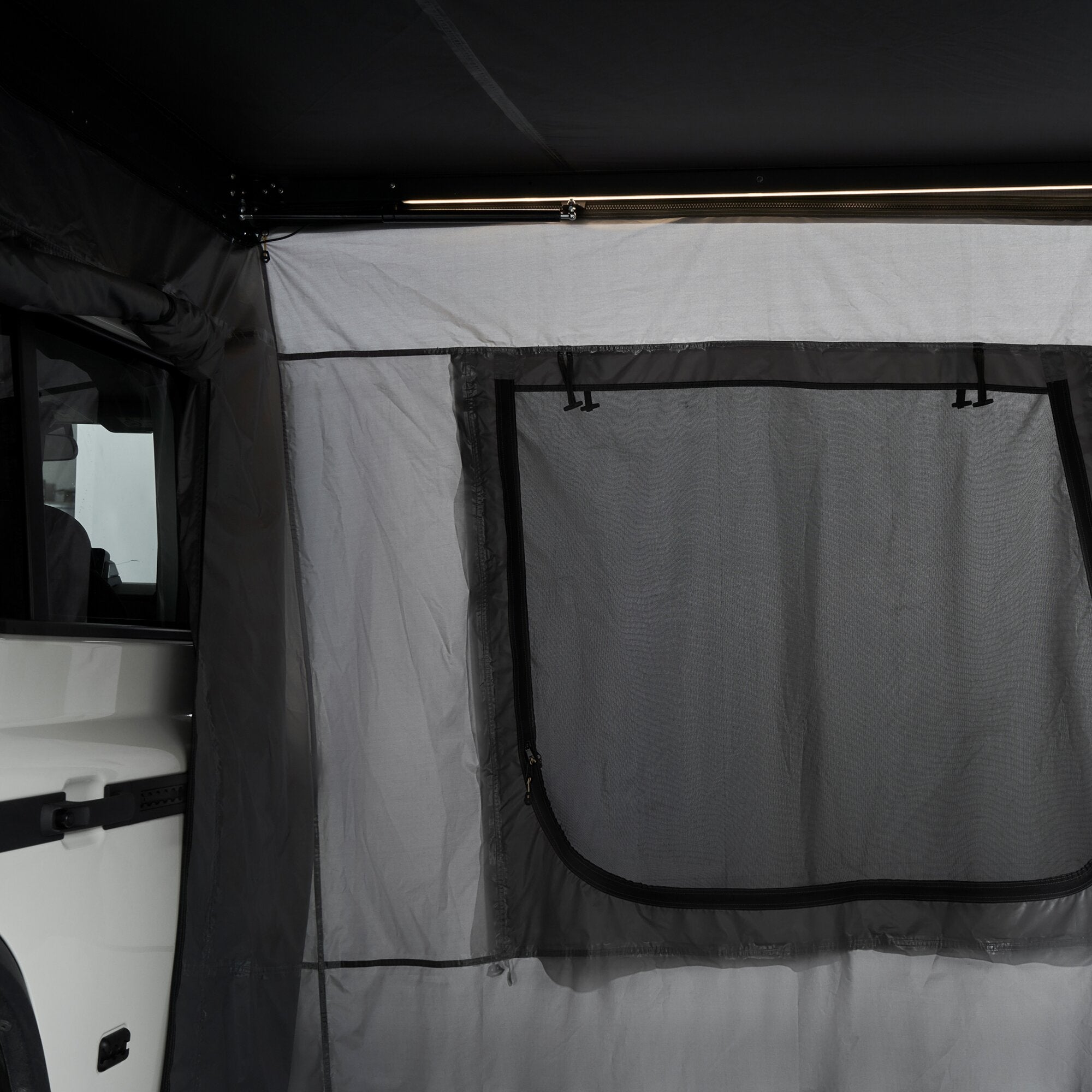 Innenansicht der Seitenwände aus grauem Gewebe einer Horizon Straight Markise mit Reißverschlüssen, Mesh-Fenster und einer oberen Leuchtleiste