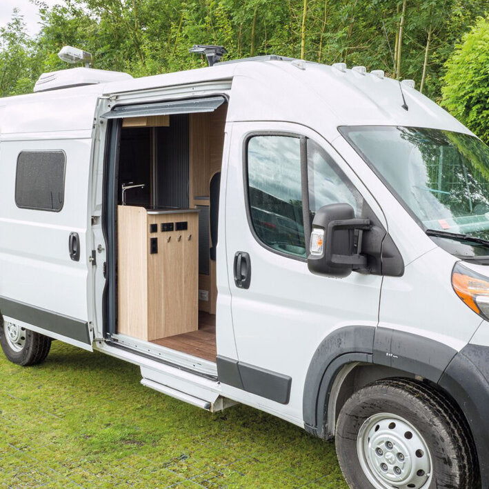 Weißer Fiat Ducato Transporter mit offener Seitentür; Innenraum zeigt eine Holzküchenzeile mit Unterschrank und Arbeitsplatte