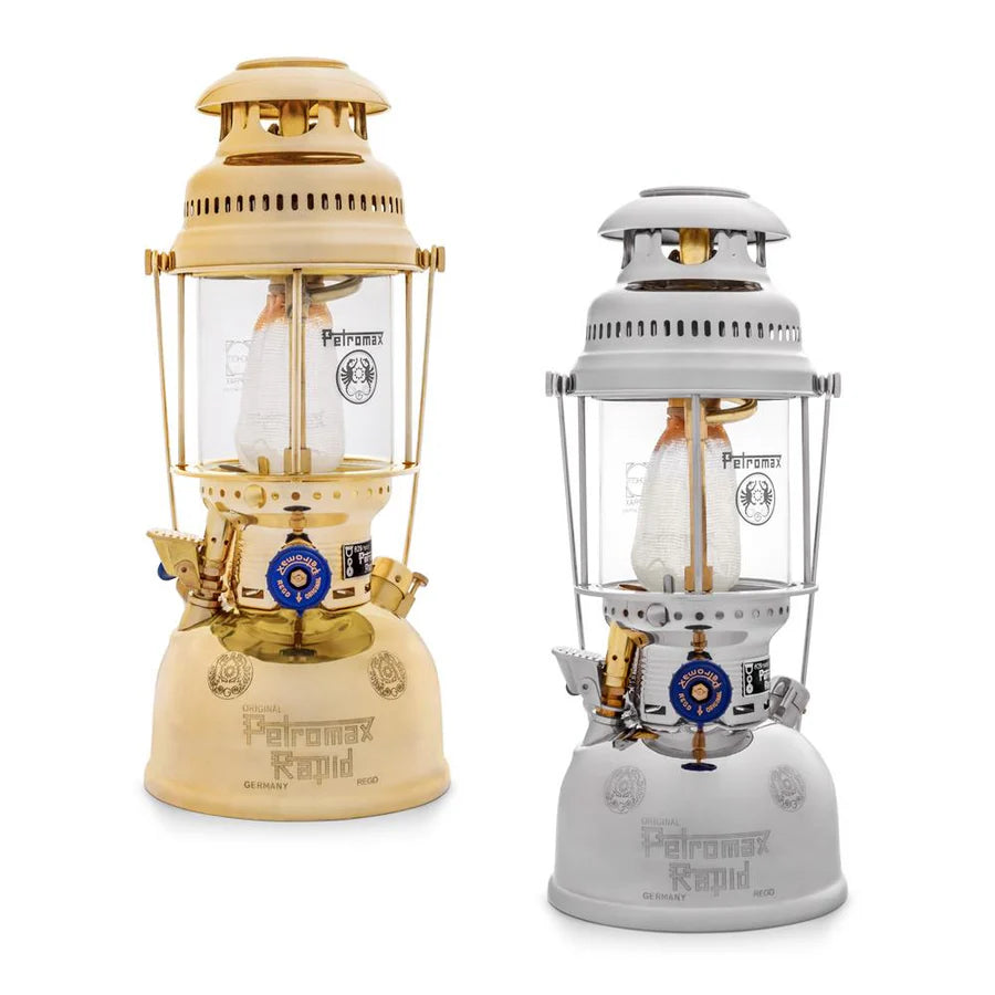 Zwei Petromax HK500 Laternen nebeneinander, eine in Beige mit goldenen Akzenten, die andere in Grau mit silbernen Details,.